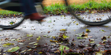 Onscherp beeld van fietser op nat wegdek met herfstbladeren