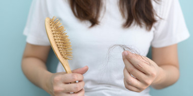 Persoon met lang haar houdt haarborstel en pluk haar in de handen