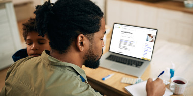 Man met kind op schoot raadpleegt Thuisarts.nl op zijn laptop.