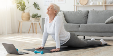 Vrouw doet yoga-oefeningen met een laptop voor haar