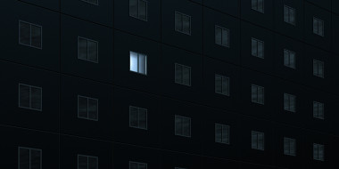 Flatgebouw in het donker met 1 verlicht raam
