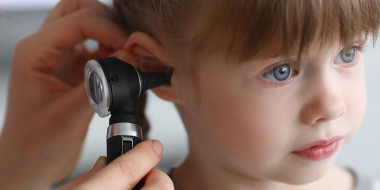 Arts kijkt met een otoscoop in oor van kind